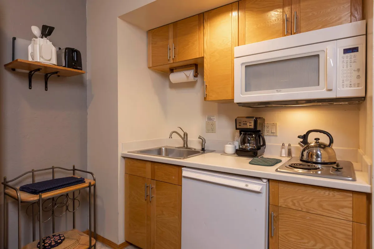 A view of the full kitchen with modern appliances, ample countertops, and a sink. The scene suggests activity and sociability, with the setup perfect for preparing home-cooked meals or enjoying coffee together. The kitchen is seamlessly connected to the living and dining spaces, reinforcing the open-concept, homey feel.